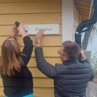 Bilde av to personer som skrur opp et skilt med teksten Erlingbua