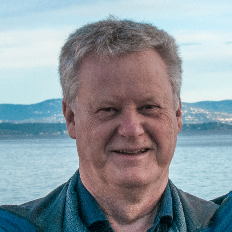 Portrettbilde av en smilende mann. Bak ham er fjorden.
