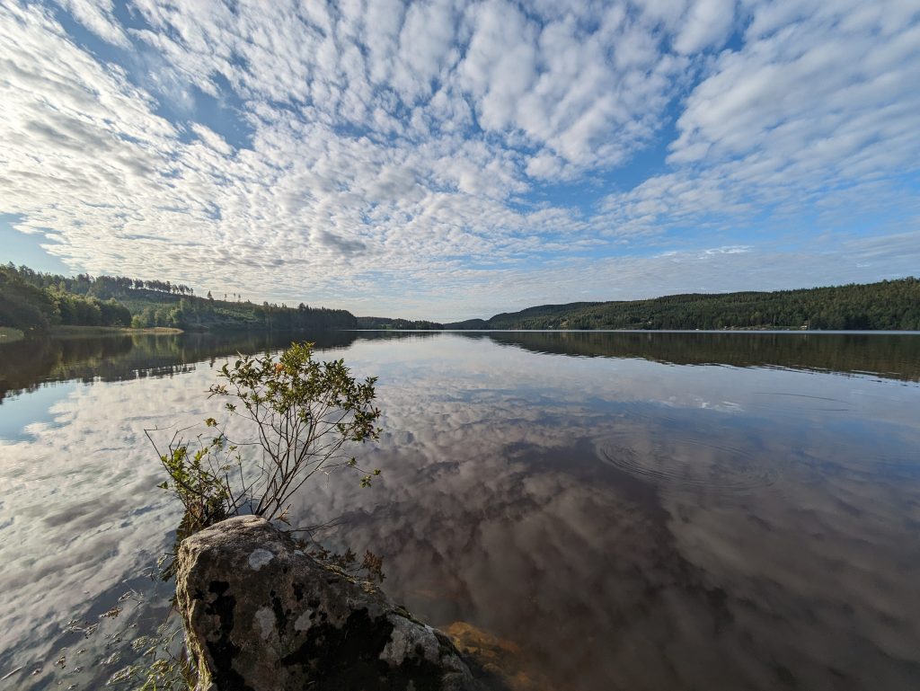 Bilde av et langstrakt vann, med skyer som speiler seg i vannet