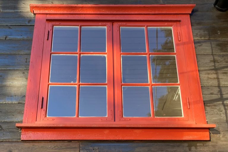 Et bilde av et vindu som har nymalte, røde karmer.